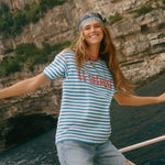 Woman on a boat, wearing the blue striped Le Sirenuse terry cloth t-shirt.