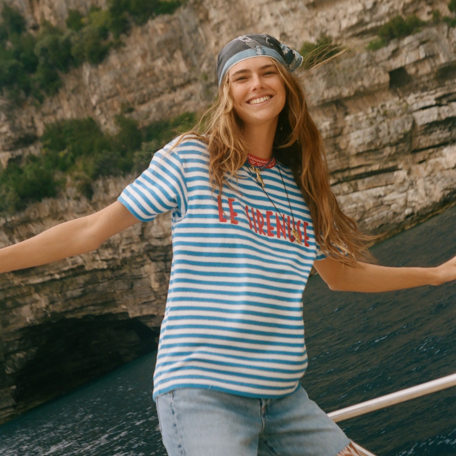 Woman on a boat, wearing the blue striped Le Sirenuse terry cloth t-shirt.