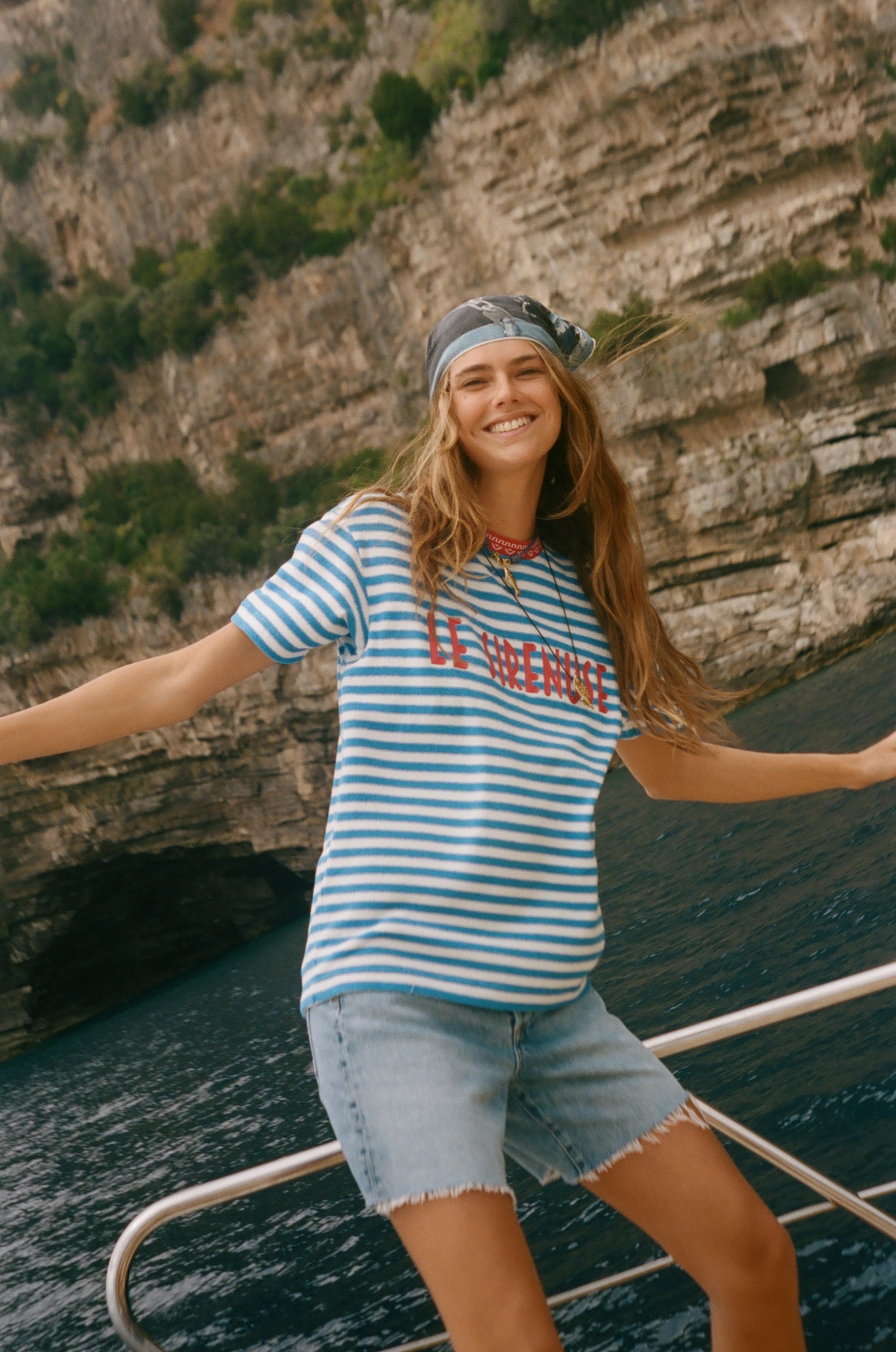 Woman on a boat, wearing the blue striped Le Sirenuse terry cloth t-shirt.