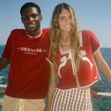 Two people wearing Le Sirenuse merchandise, standing by the ocean. 