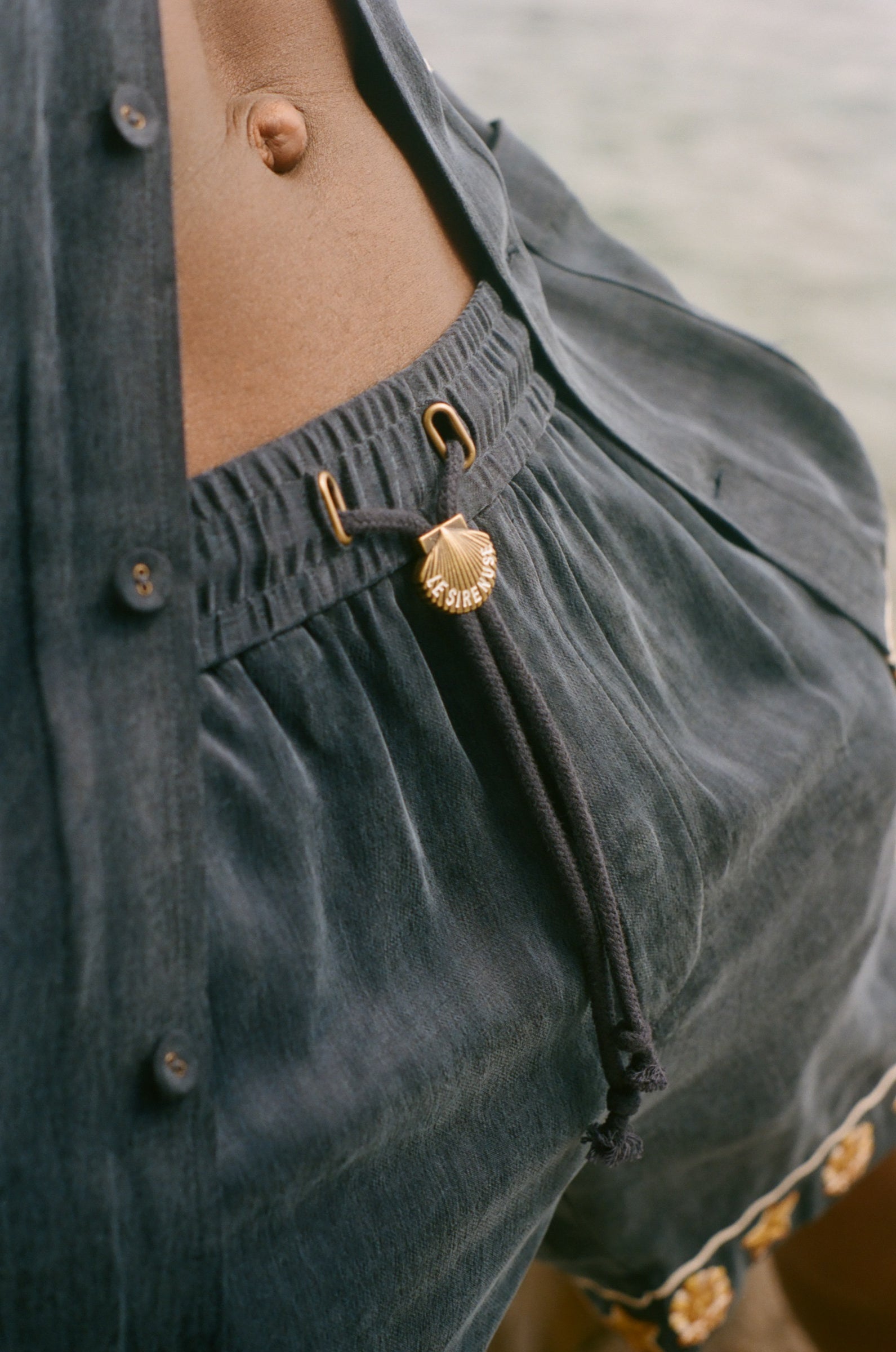 Close-up of dark blue shorts with gold decorative elements.
