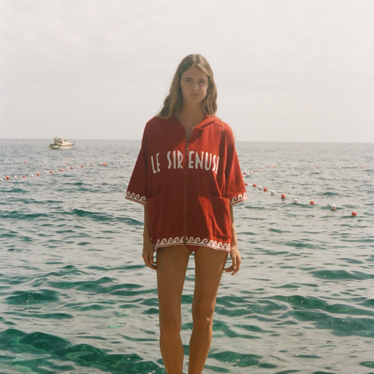 Woman wearing Le Sirenuse Beach Towel Top, standing in front of the ocean.