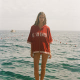 Woman wearing Le Sirenuse Beach Towel Top, standing in front of the ocean.