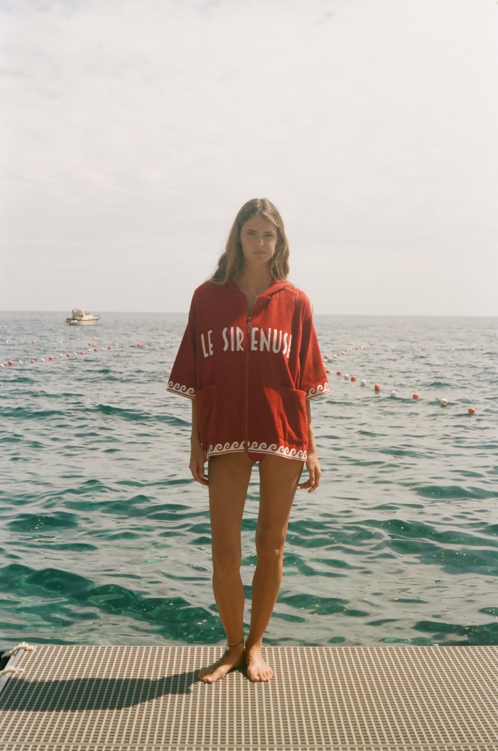 Woman wearing Le Sirenuse Beach Towel Top, standing in front of the ocean.