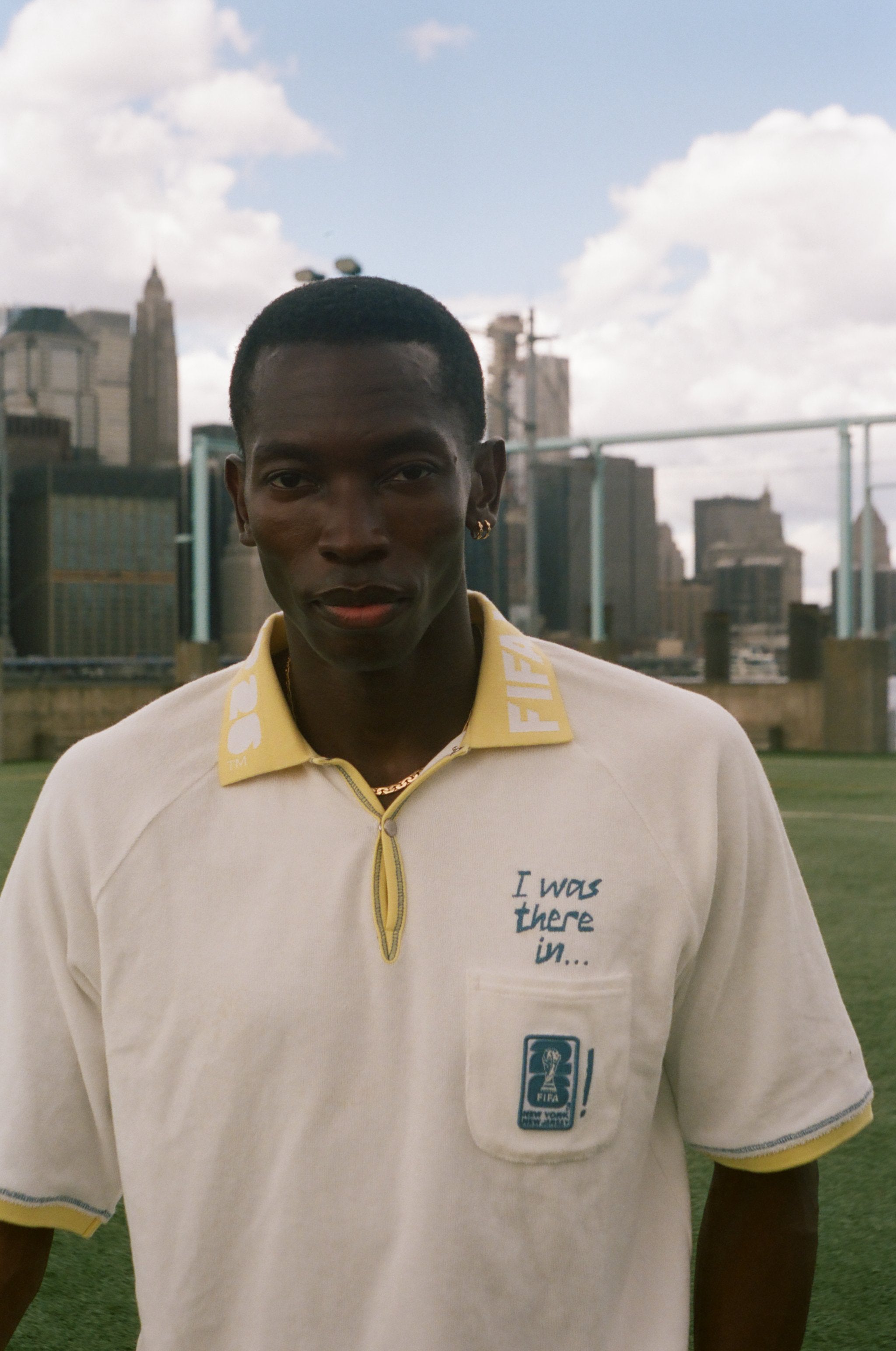 Man wearing a white polo shirt with a yellow collar, featuring FIFA 26 logo.