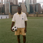 Man holding a soccer ball on a soccer field with a city skyline in the background