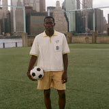 Man holding a soccer ball on a soccer field with a city skyline in the background