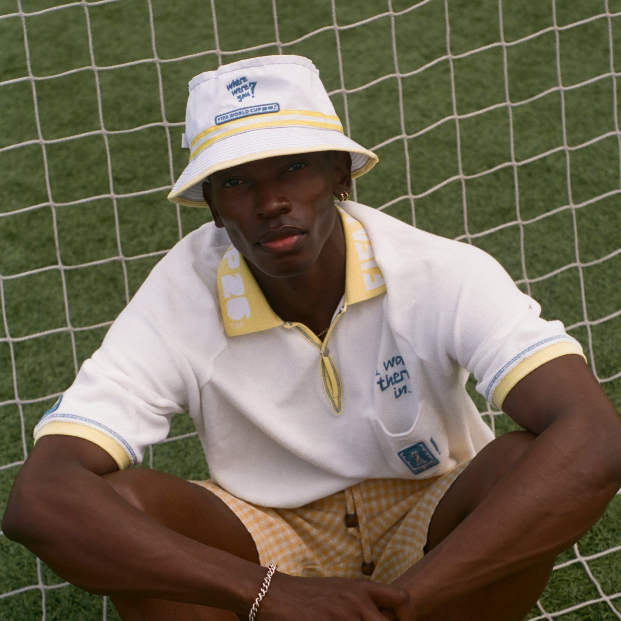 Person wearing a white bucket hat and polo shirt sitting on grass.