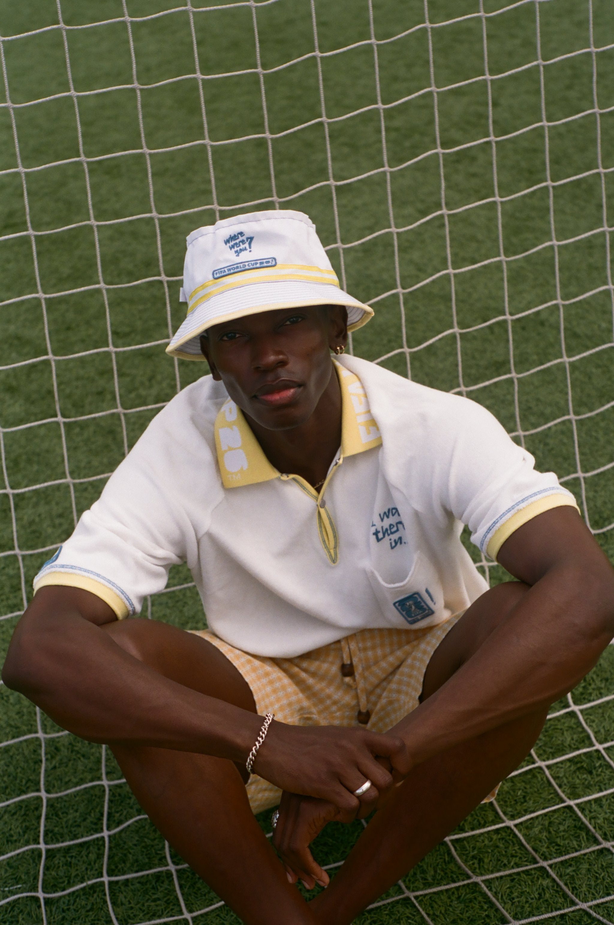 Person wearing a white bucket hat and polo shirt sitting on grass.