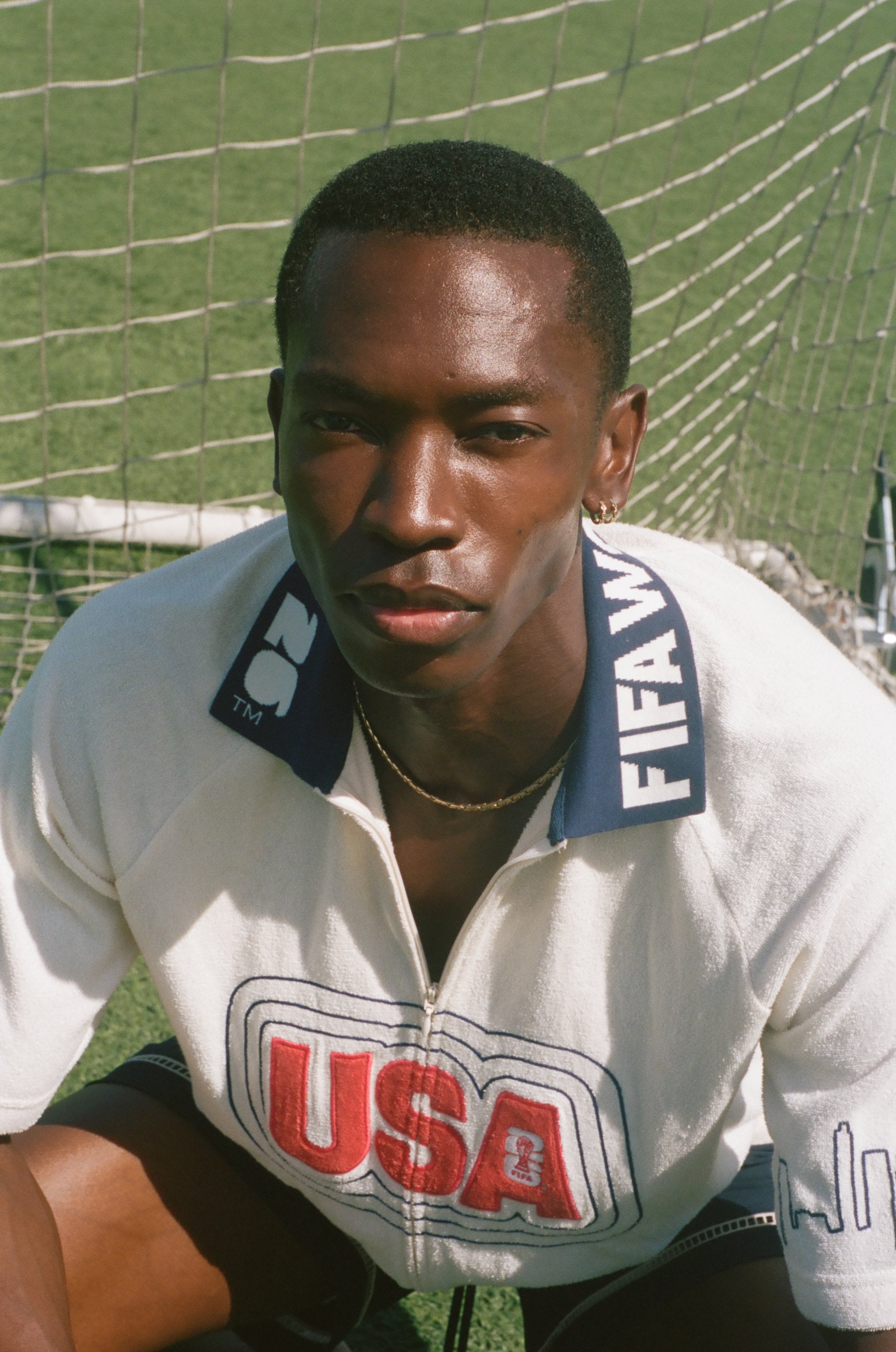 Person wearing a white cabana shirt with 'USA' and FIFA logo on a grass field.