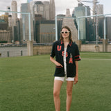 Person wearing a 'USA' cabana with a soccer ball on a soccer field with city skyline in the background