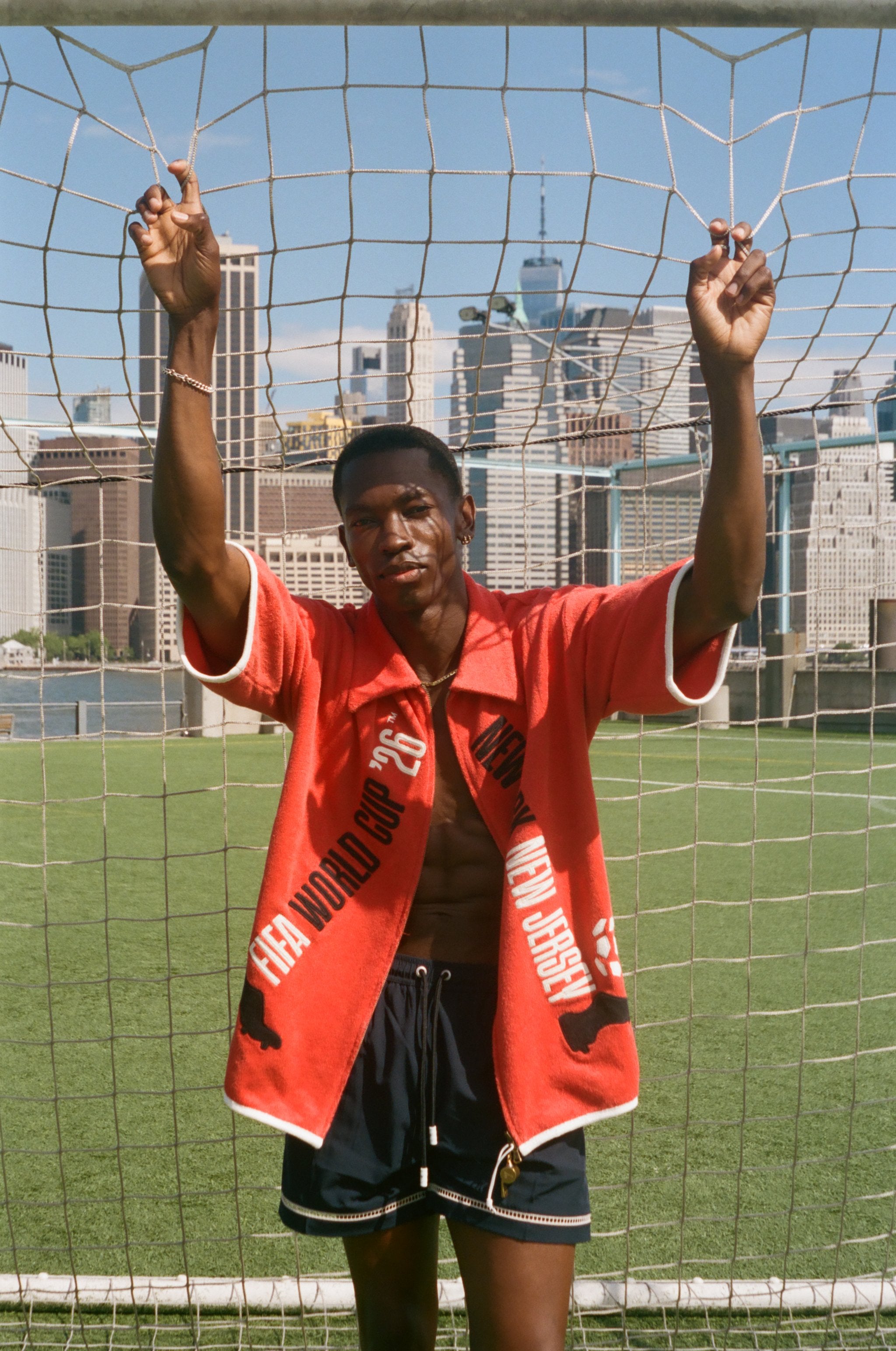Man wearing red FIFA fancy footwork cabana, standing in front of a soccer net.