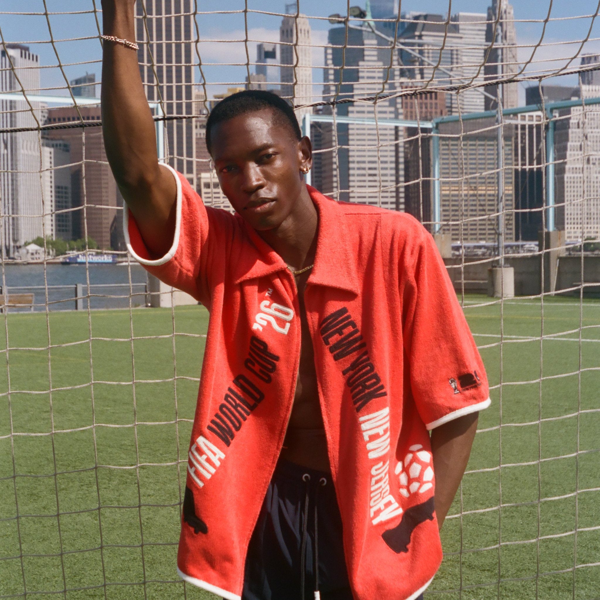 Man wearing red FIFA fancy footwork cabana, standing in front of a soccer net.