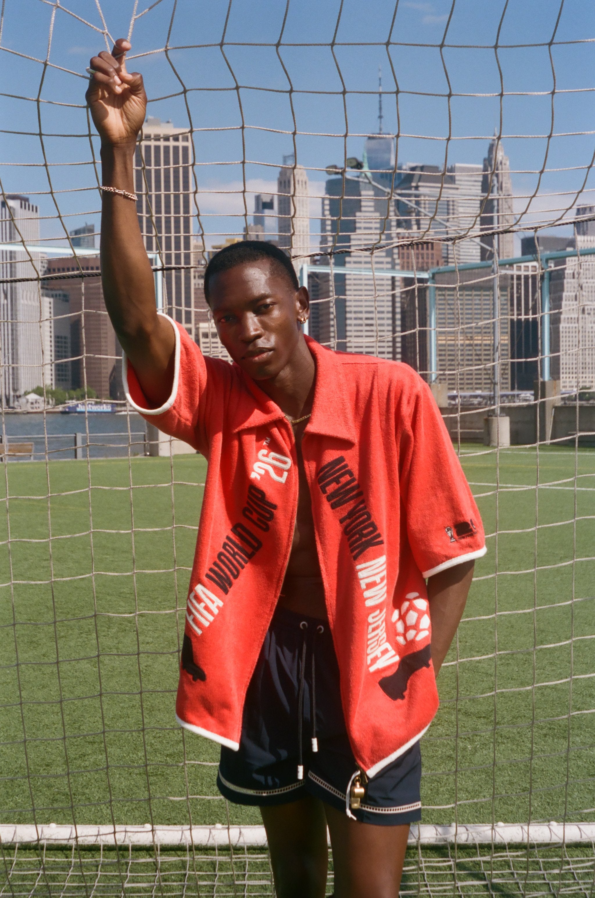 Man wearing red FIFA fancy footwork cabana, standing in front of a soccer net.