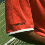 Red cabana with 'Tombolo' logo on the wearer's sleeve. 