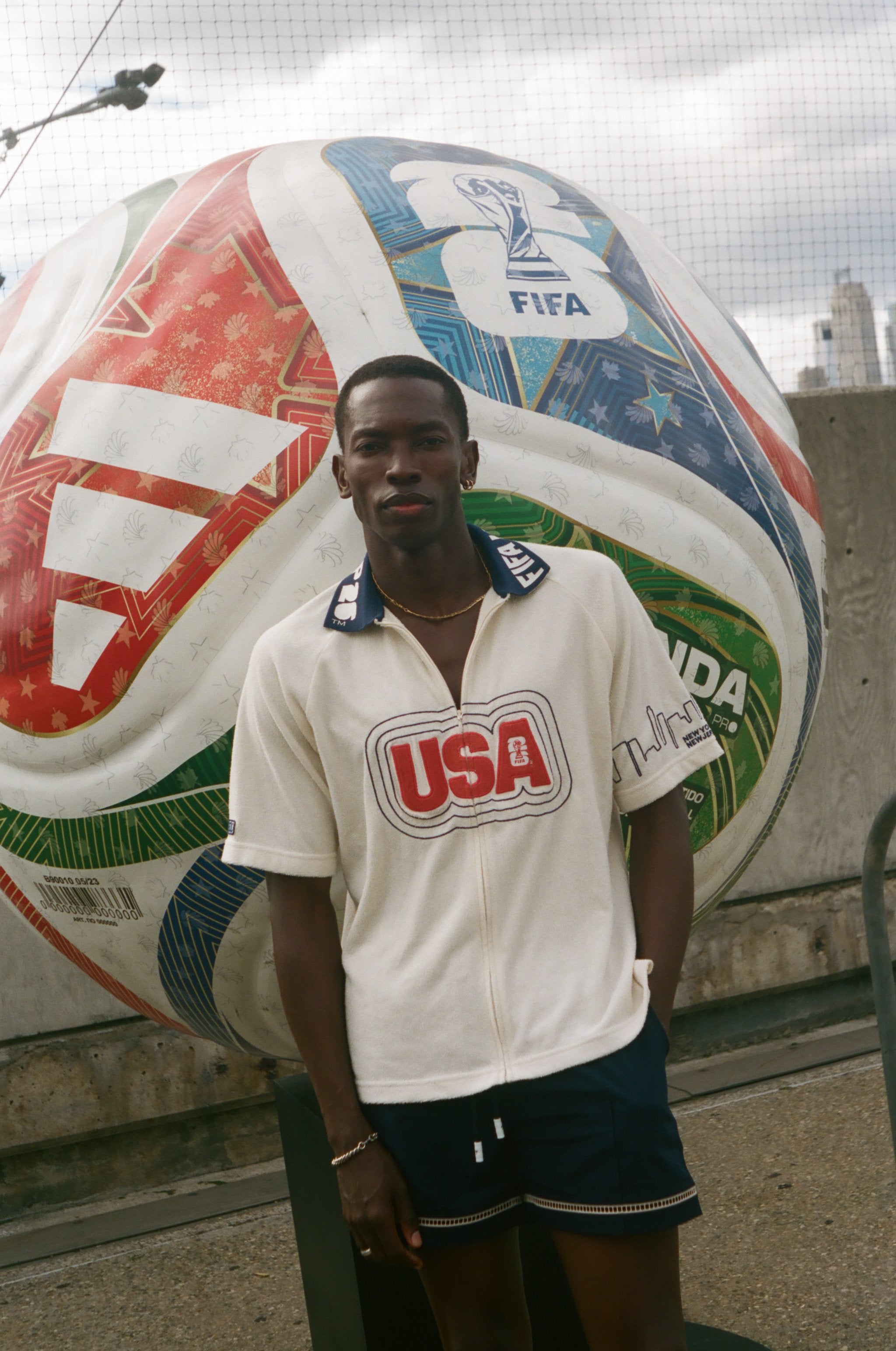 Man standing in front of a large soccer ball with FIFA branding, wearing Tombolo USA cabana. 