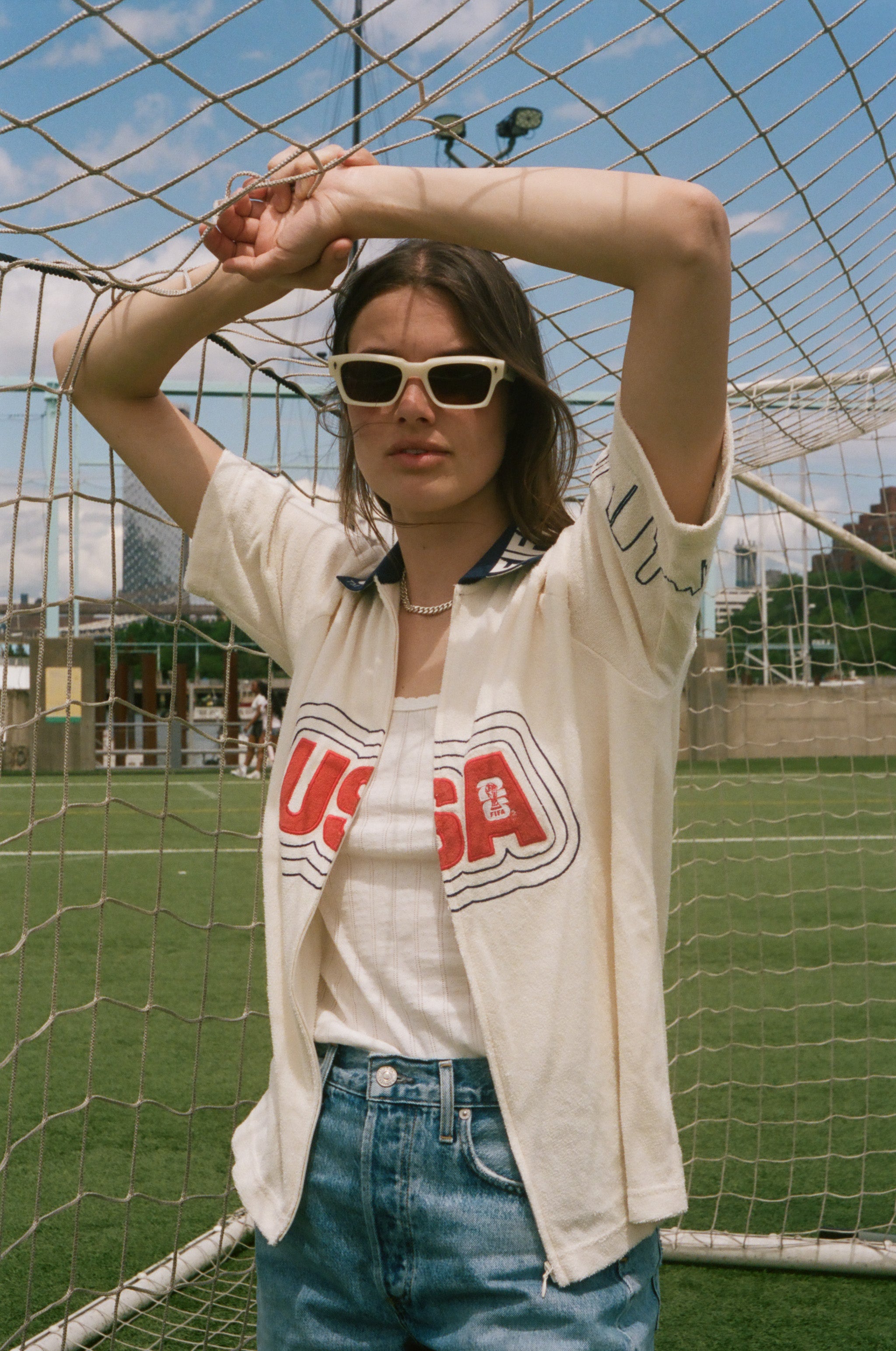 Person wearing sunglasses and a USA cabana shirt in front of a soccer goal.