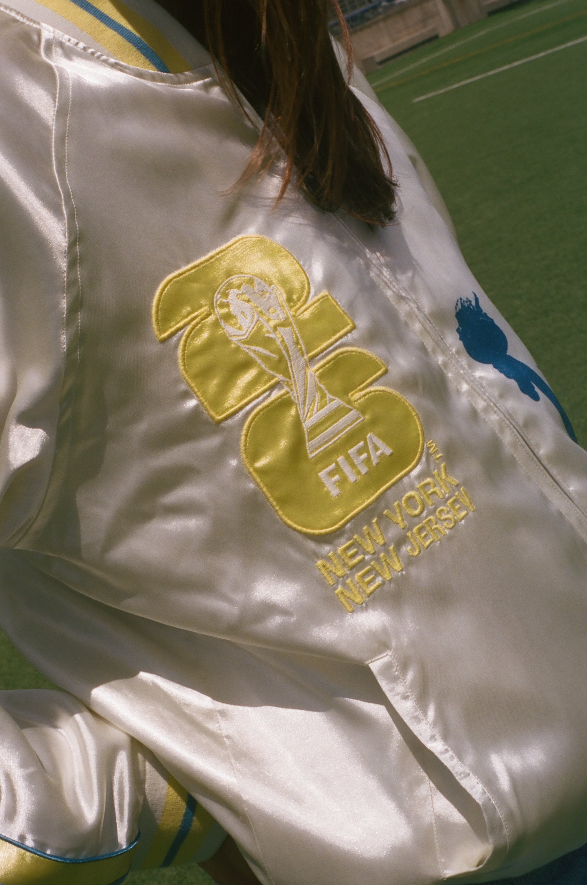 Close-up of a white jacket with FIFA logo and 'New York New Jersey' text on a grassy field.