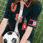 Person wearing a USA-themed shirt holding a soccer ball on grass
