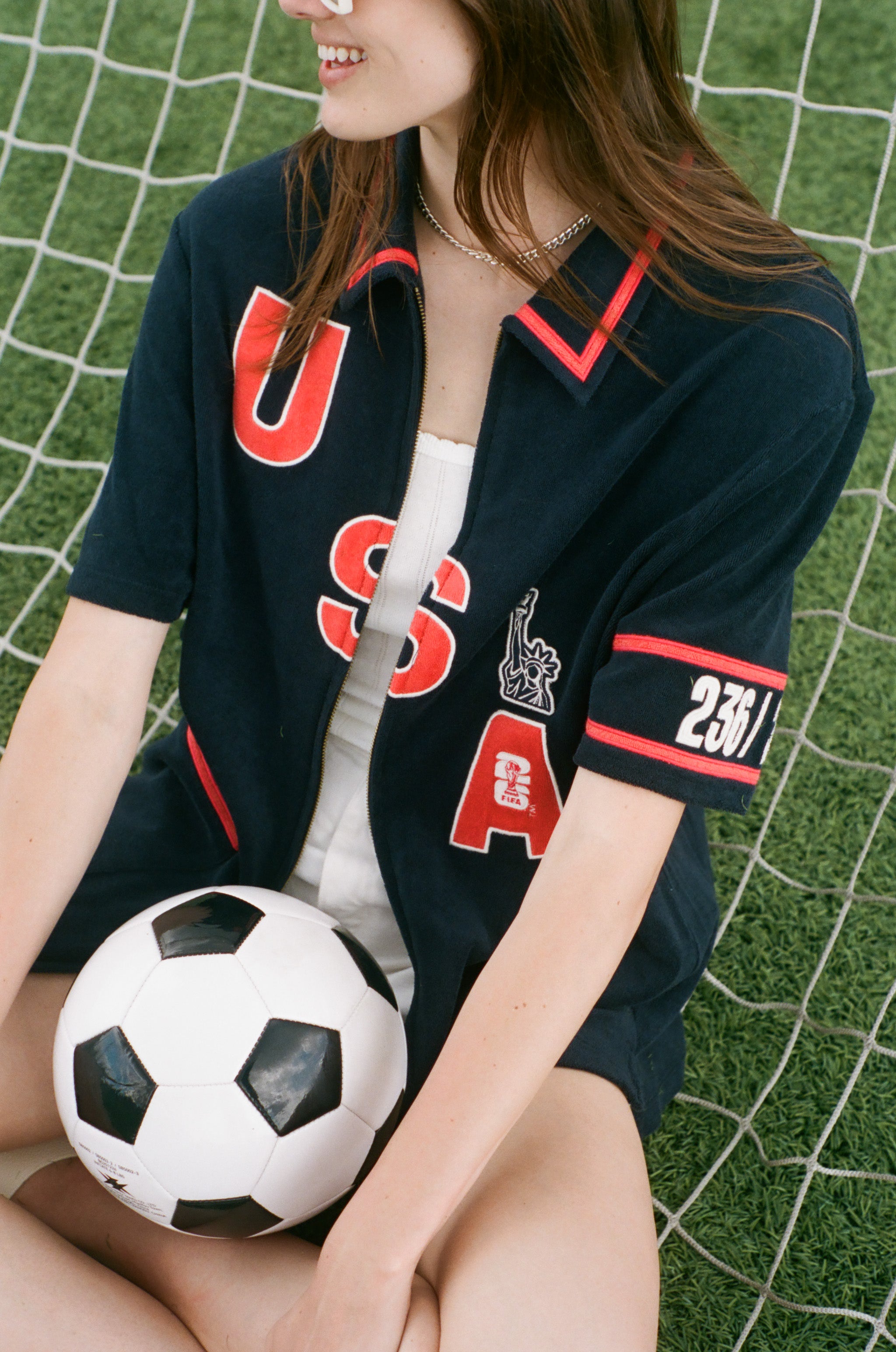 Person wearing a USA-themed shirt holding a soccer ball on grass