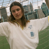 Woman wearing "Where were you?" FIFA Cabana shirt, leaning against a soccer net. 