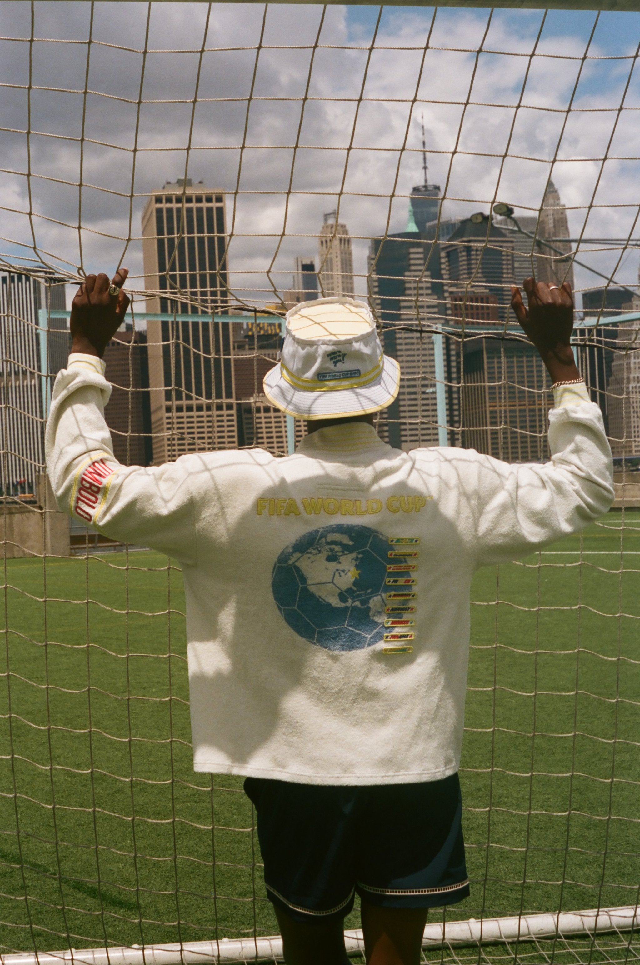 Man showing off the back off his FIFA World Cup long sleeve cabana shirt and bucket hat. 