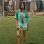 Woman wearing the teal Stars and Stripes Cabana oversized and open, standing on a soccer field.