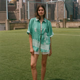Woman wearing the teal Stars and Stripes Cabana oversized and open, standing on a soccer field.