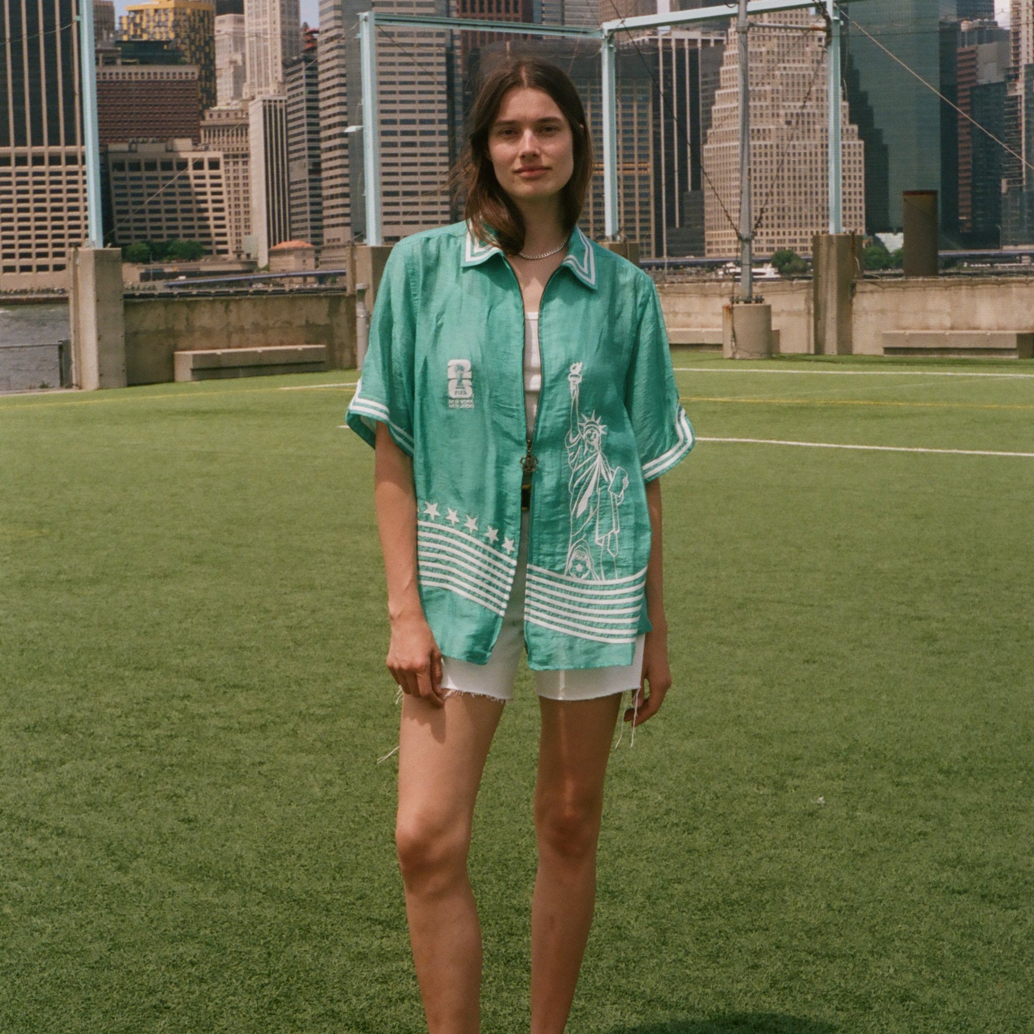 Woman wearing the teal Stars and Stripes Cabana oversized and open, standing on a soccer field.