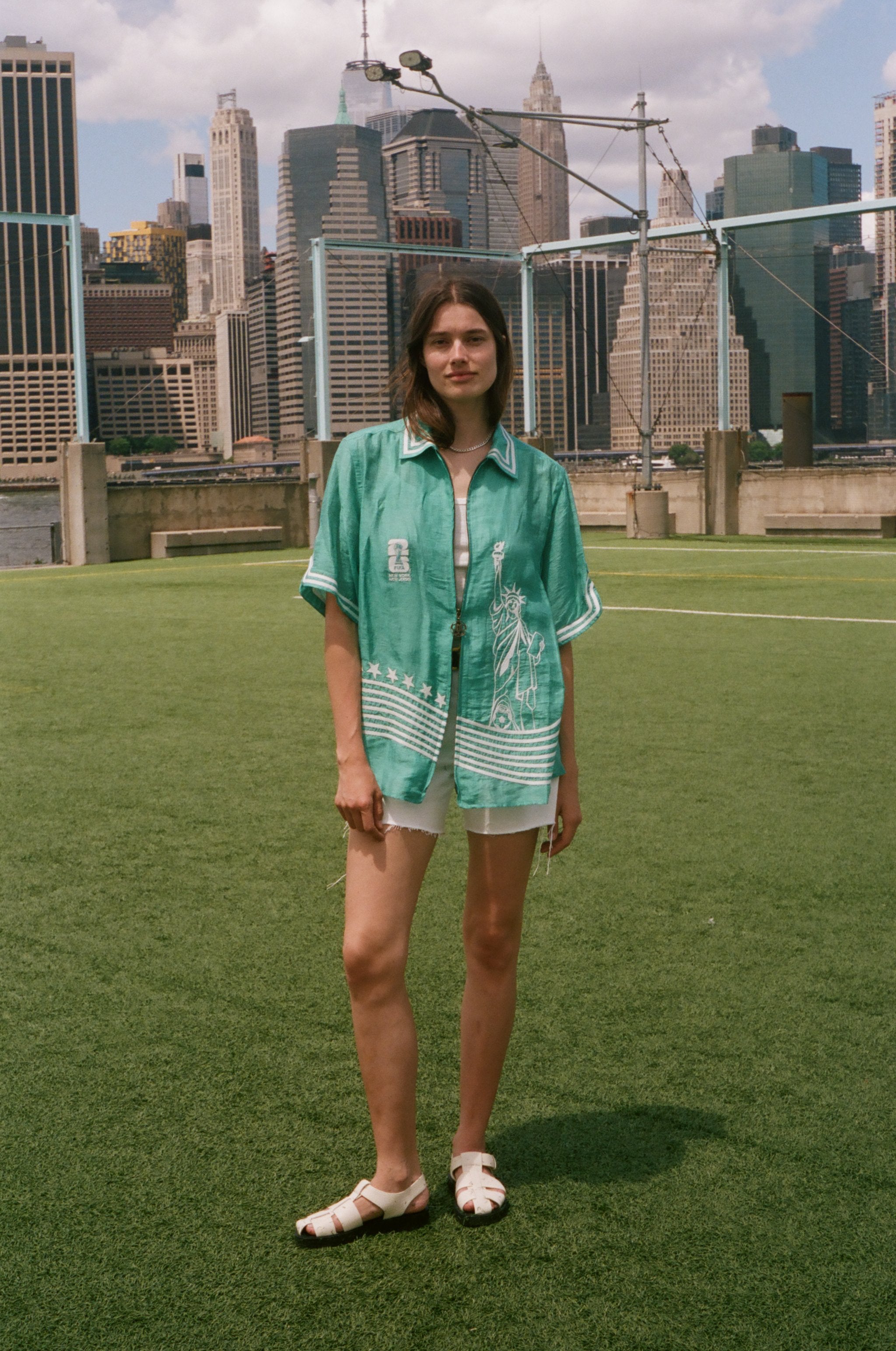 Woman wearing the teal Stars and Stripes Cabana oversized and open, standing on a soccer field.