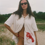 Woman wearing Lobster shirt oversized on the beach.