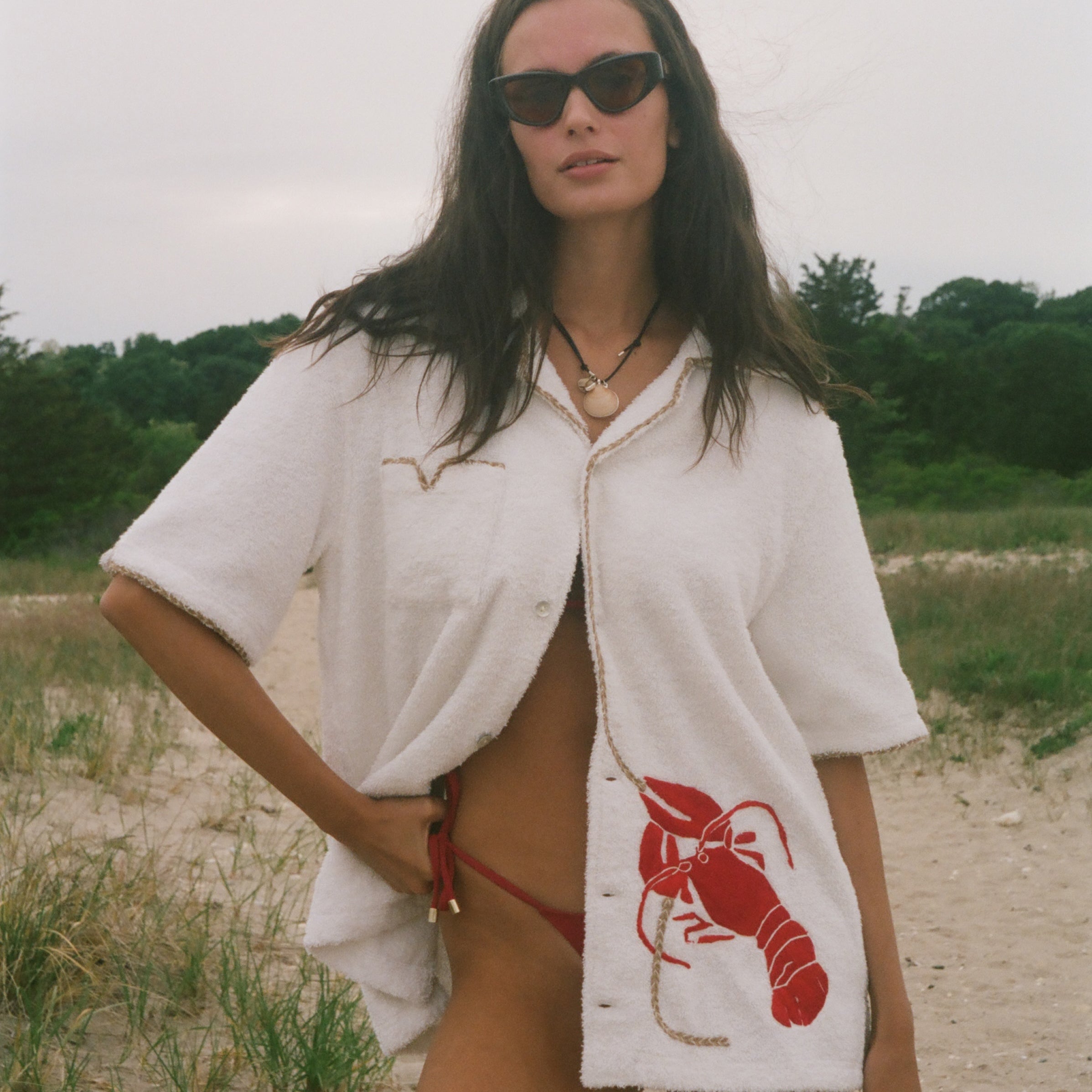 Woman wearing Lobster shirt oversized on the beach.