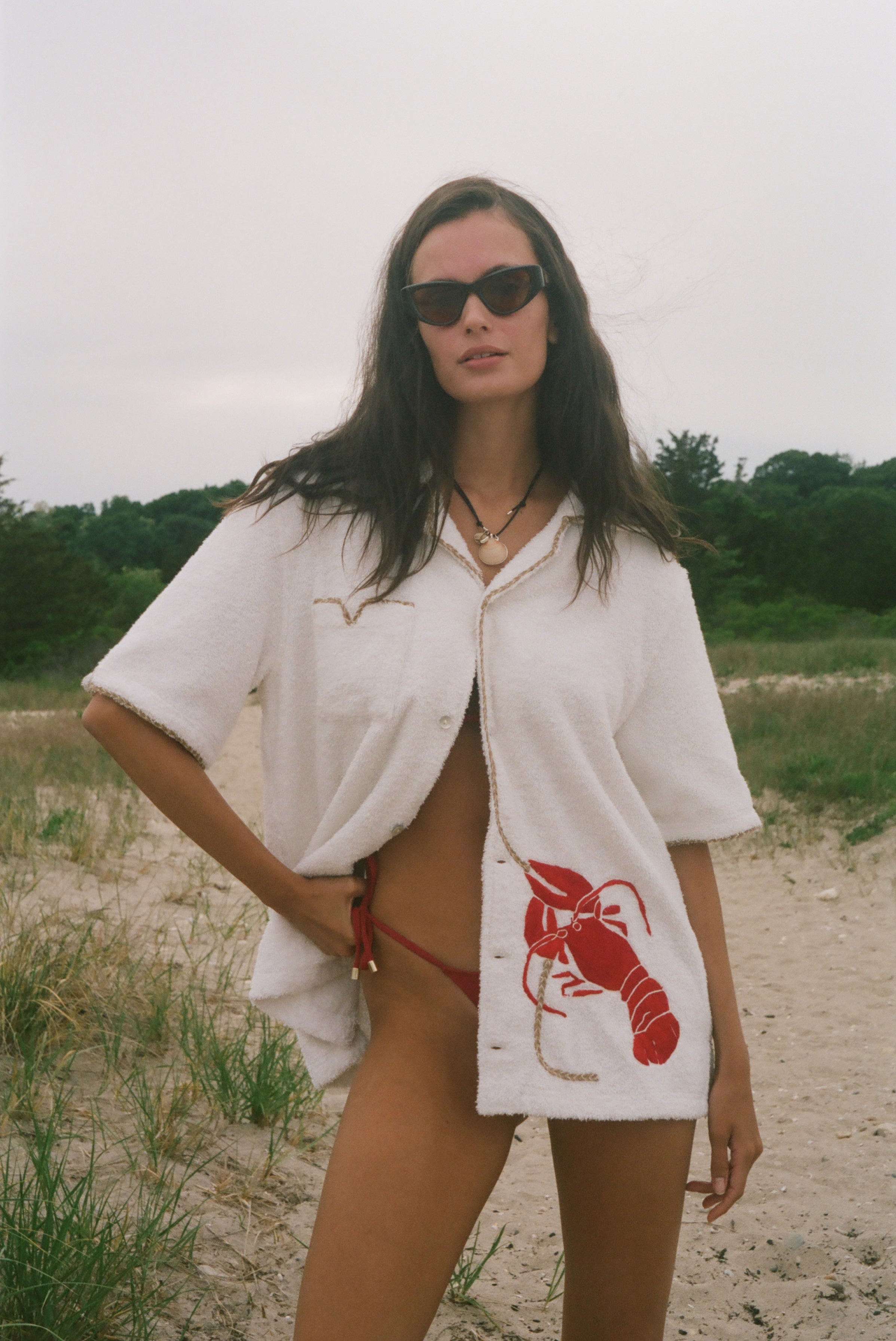 Woman wearing Lobster shirt oversized on the beach.