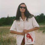 Woman wearing Lobster shirt oversized on the beach.