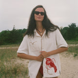 Woman wearing Lobster shirt oversized on the beach.