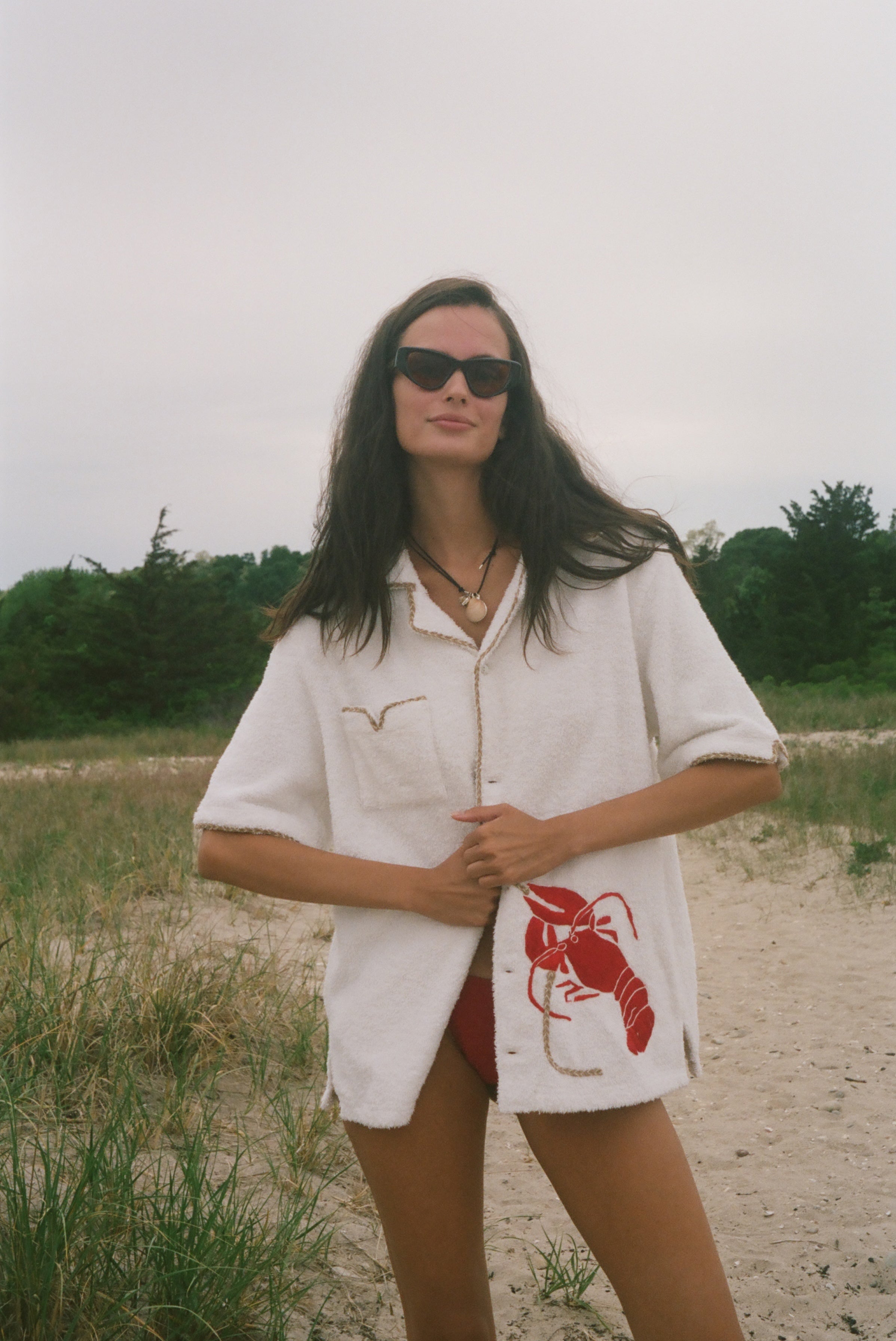 Woman wearing Lobster shirt oversized on the beach.