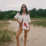 Woman wearing Lobster shirt oversized on the beach.