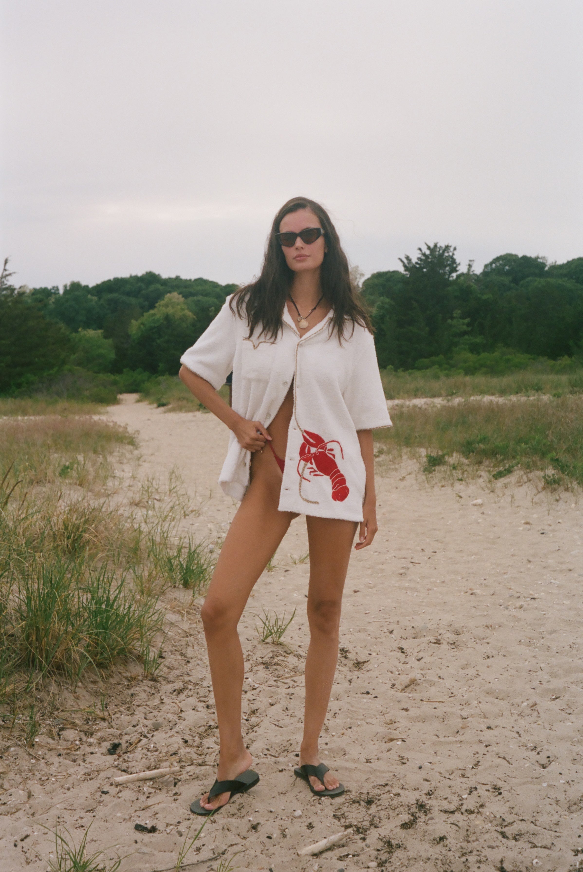 Woman wearing Lobster shirt oversized on the beach.