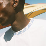 A close-up side profile of a man wearing a white branzino t-shirt.