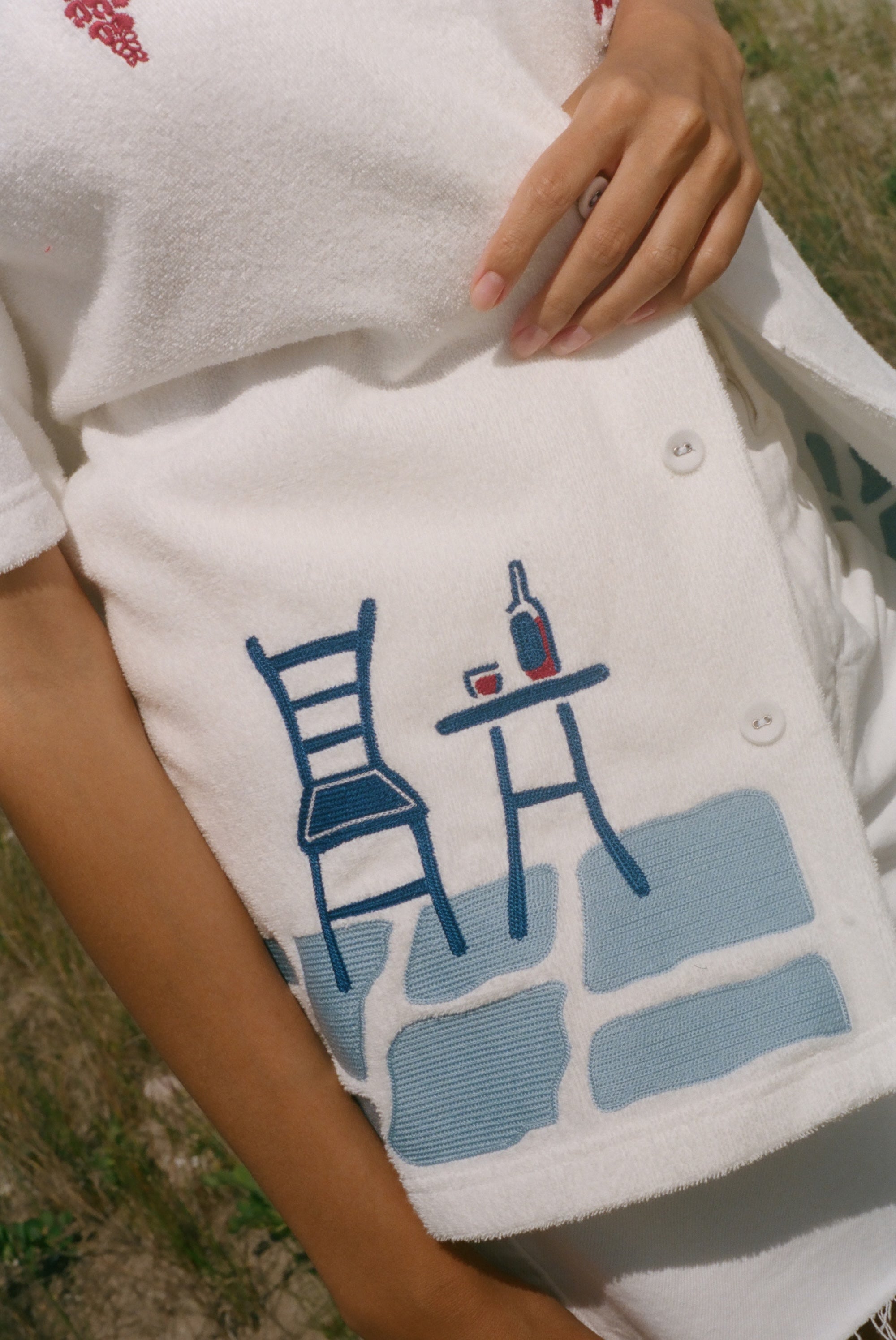 Close-up of the cafe table and bottle of wine embroidery on the lower left side.