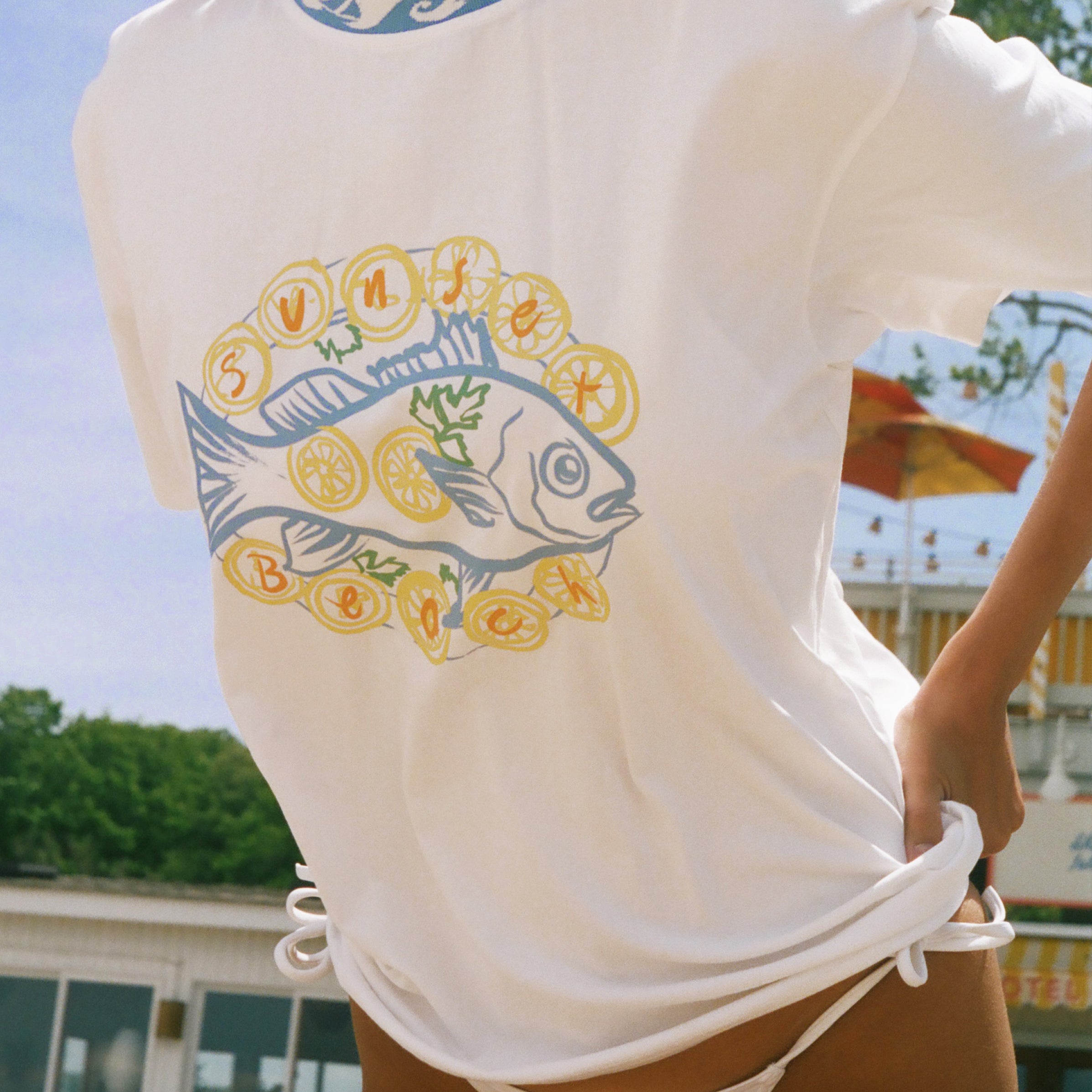 A woman wearing a white short-sleeve t-shirt with a graphic of a blue fish