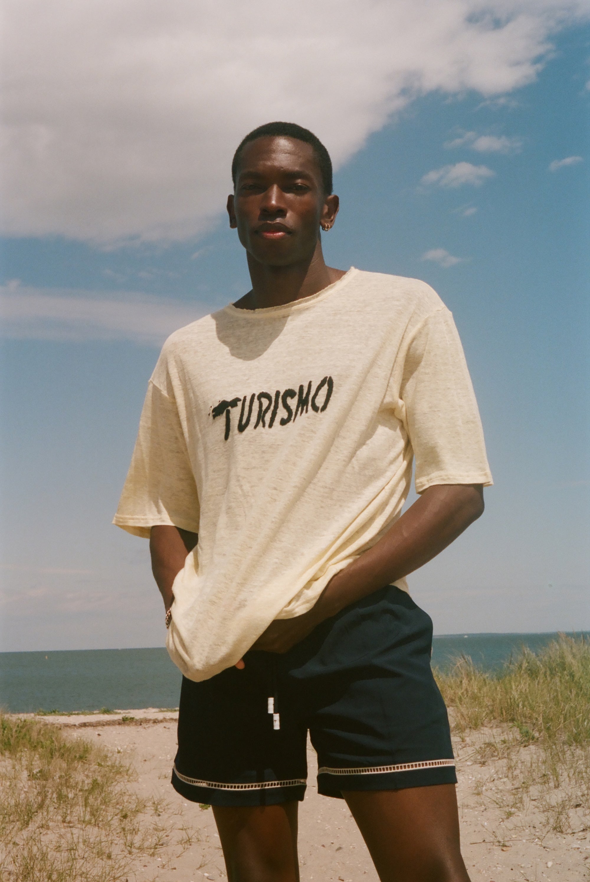 Man wearing a yellow t-shirt with 'Turismo' text on a beach