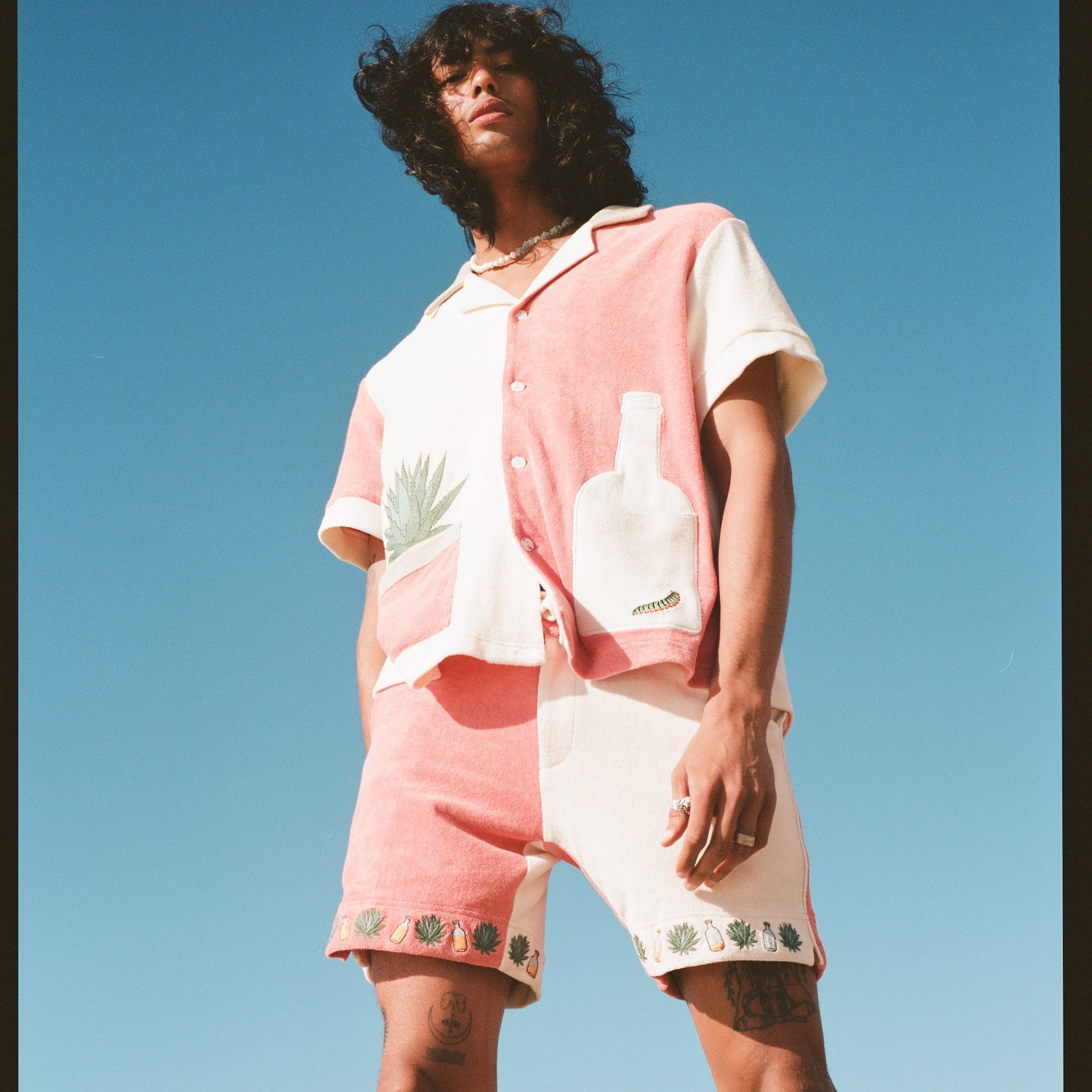 Male Model pictured from below, wearing full 'Gusanito' Cabana Set with his brown hair blowing in the wind.