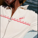 Female model wearing a large beige sunhat sitting on a boat while wearing the 'Boston Whaler' Cabana (white).