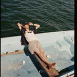 Male model wearing the 'Boston Whaler' Cabana (navy) while lying on a boat with his head over the bow, and one arm supporting it, shot on a background of the water.