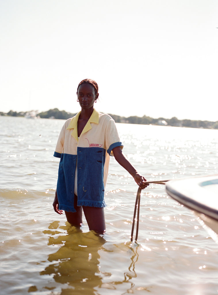 Female model holding a rope attached to a boat while standing in knee-high water wearing the 'boston whaler' no nibbles cabana.