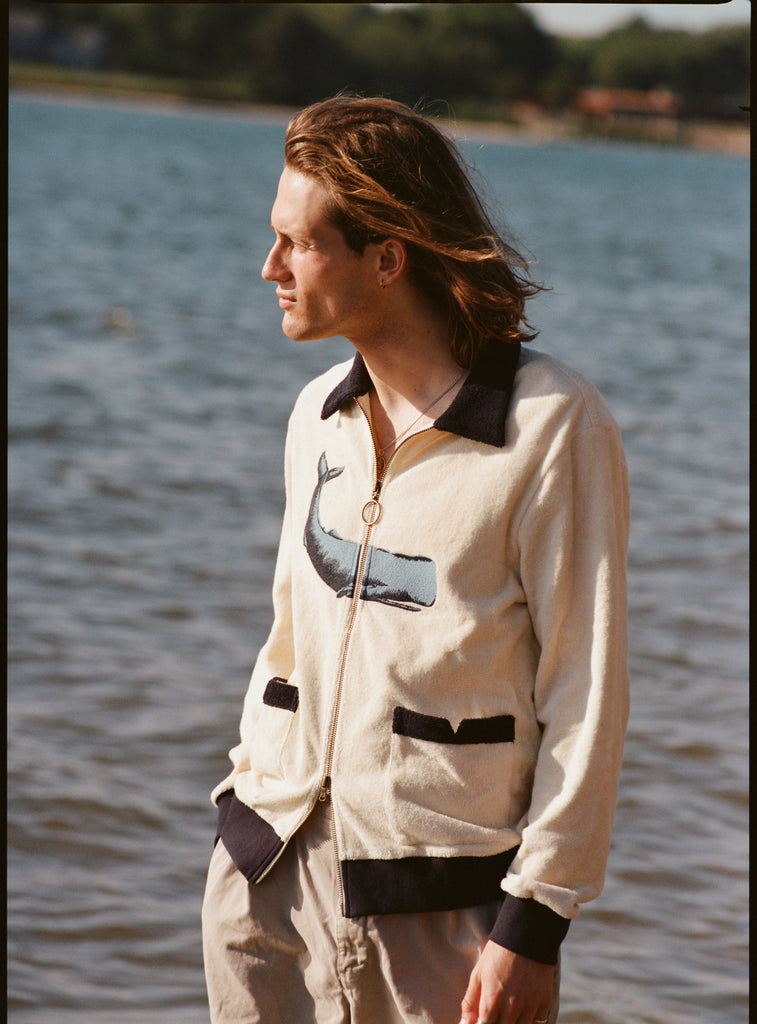Man standing in front of water, wearing Long Sleeve 'Blubber' Cabana, and staring out to the side. 