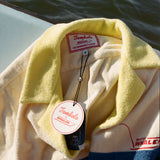 Close-up product image of the 'Boston Whaler' No nibbles cabana interior tag with both Tombolo and Boston Whaler logos, and text that reads: 'the unsinkable legend.'