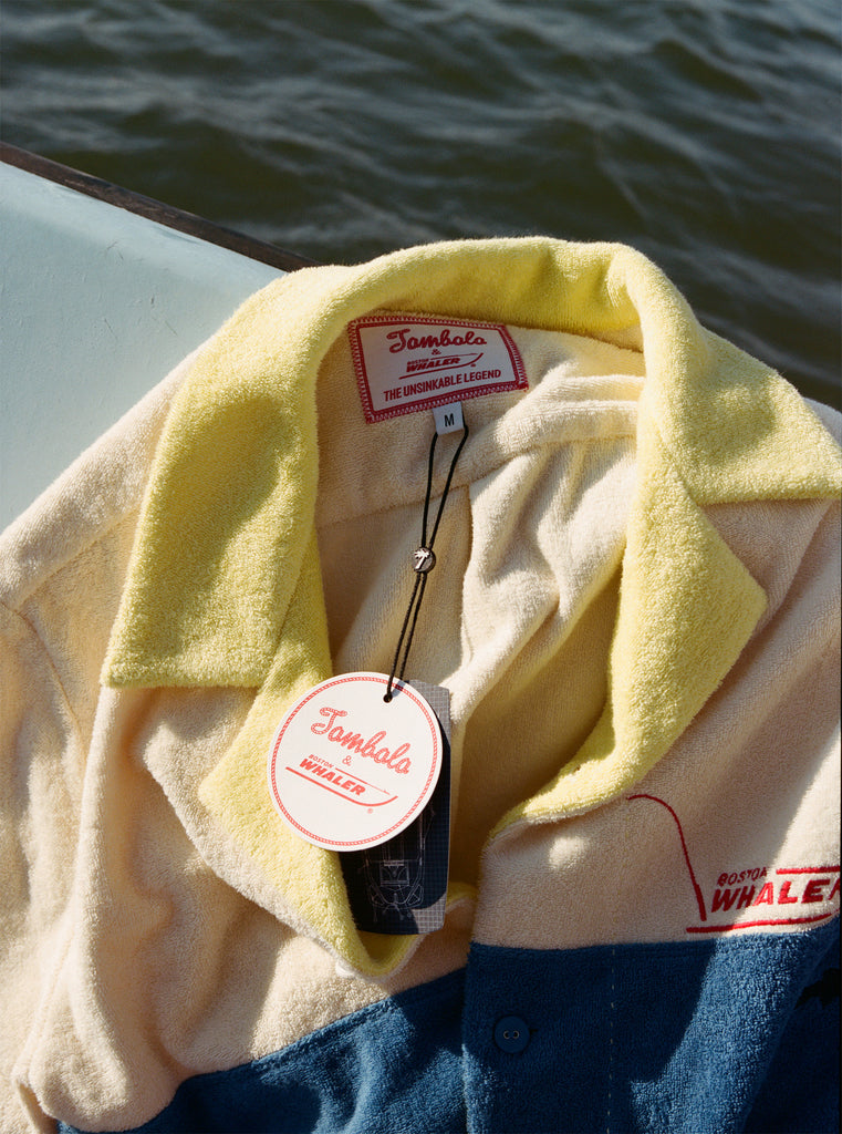 Close-up product image of the 'Boston Whaler' No nibbles cabana interior tag with both Tombolo and Boston Whaler logos, and text that reads: 'the unsinkable legend.'