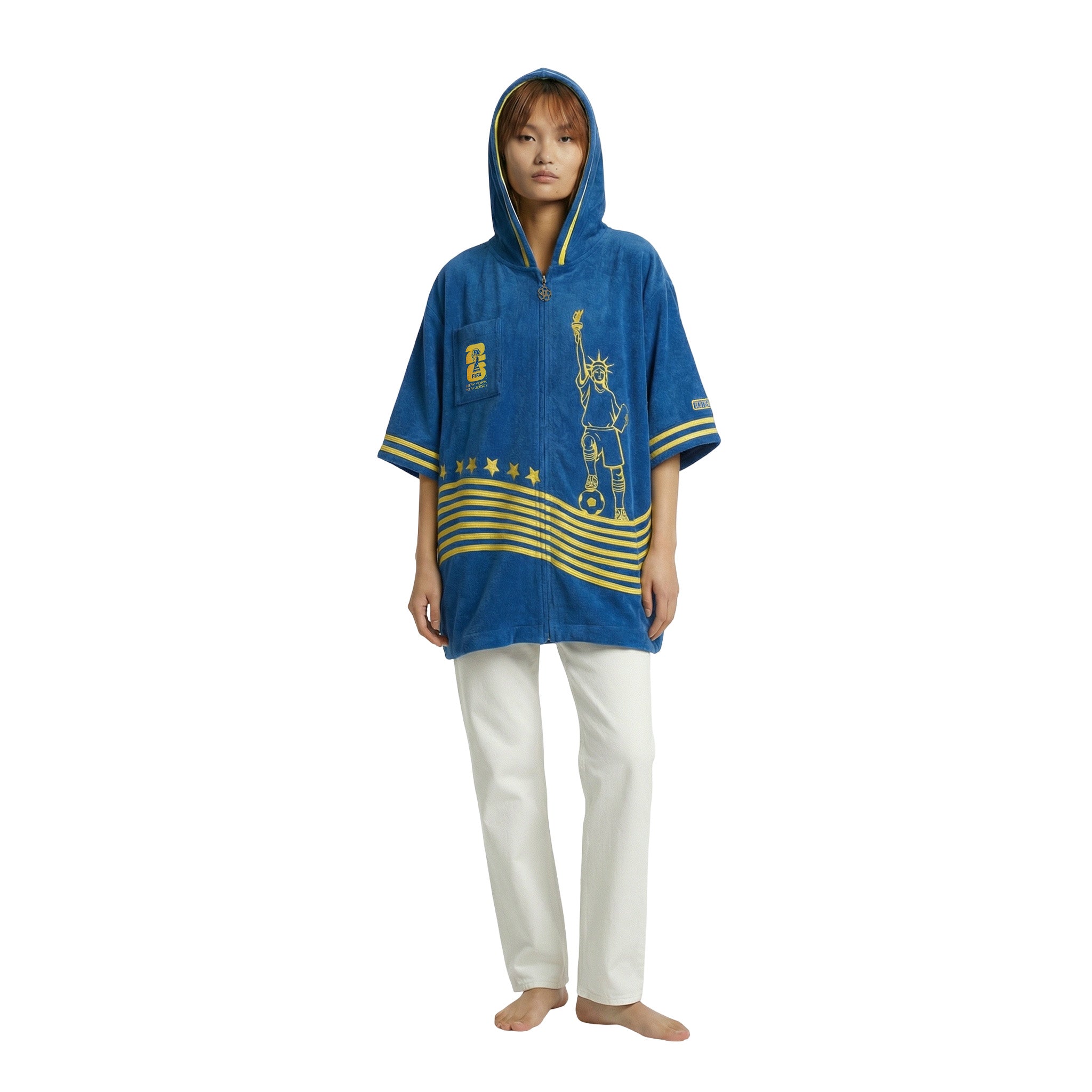 Model wearing a blue terry cloth hooded zip beach towel top with yellow stripes, chest patch, and Statue of Liberty soccer embroidery.